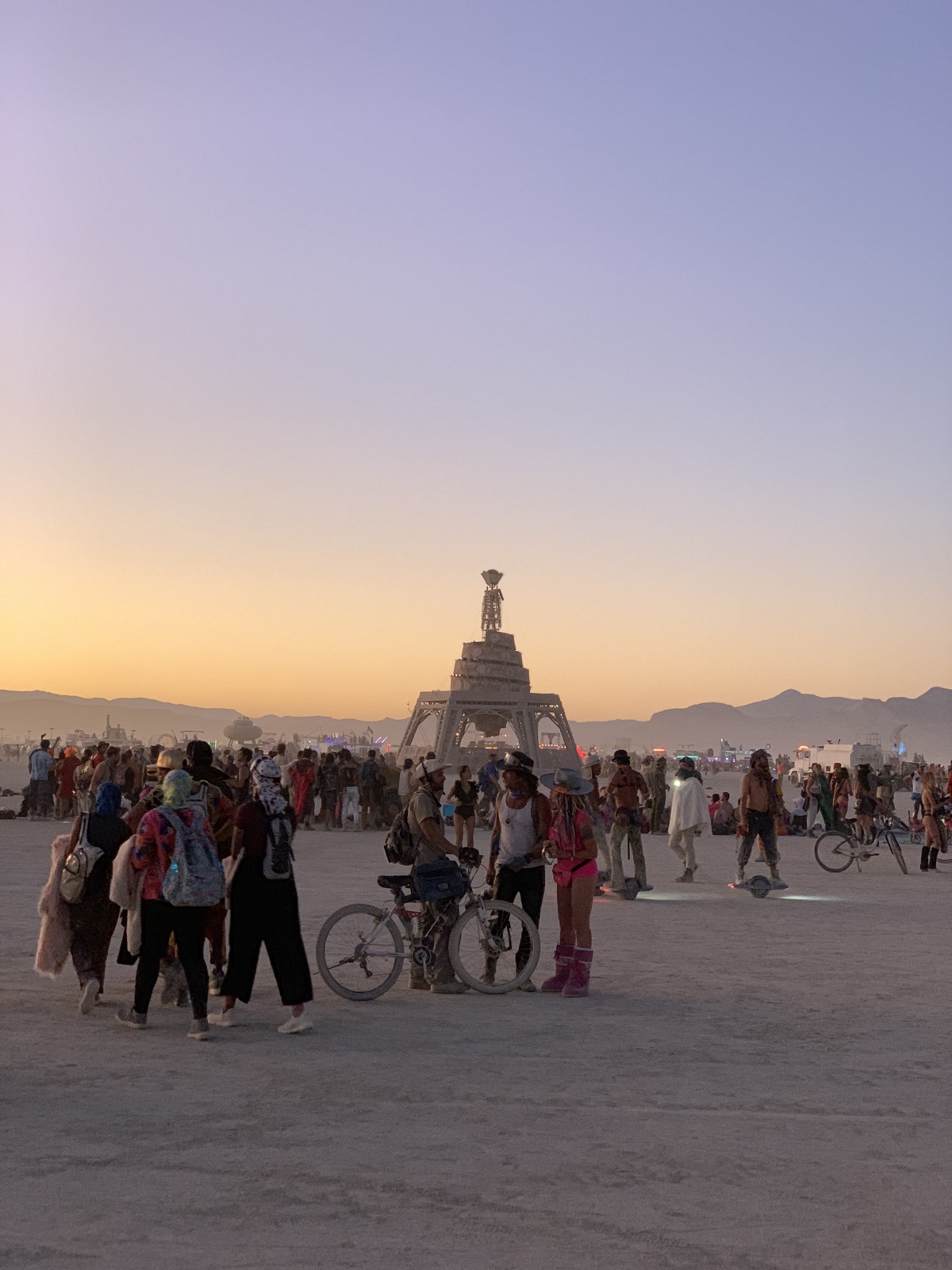 The Man at sunset with the playa crowd at Burning Man, Black Rock Desert, Nevada, photographed by Lee Hnetinka