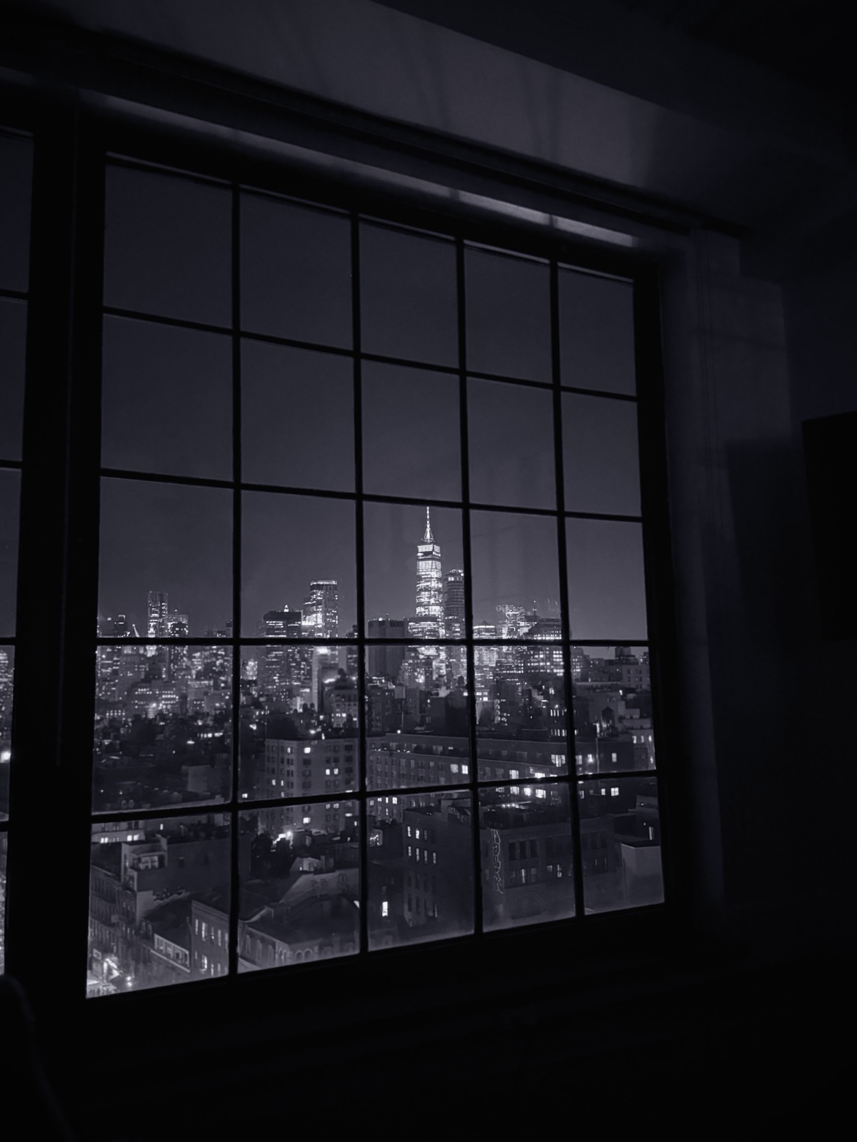 New York City at night through a window, in black and white, photographed by Lee Hnetinka